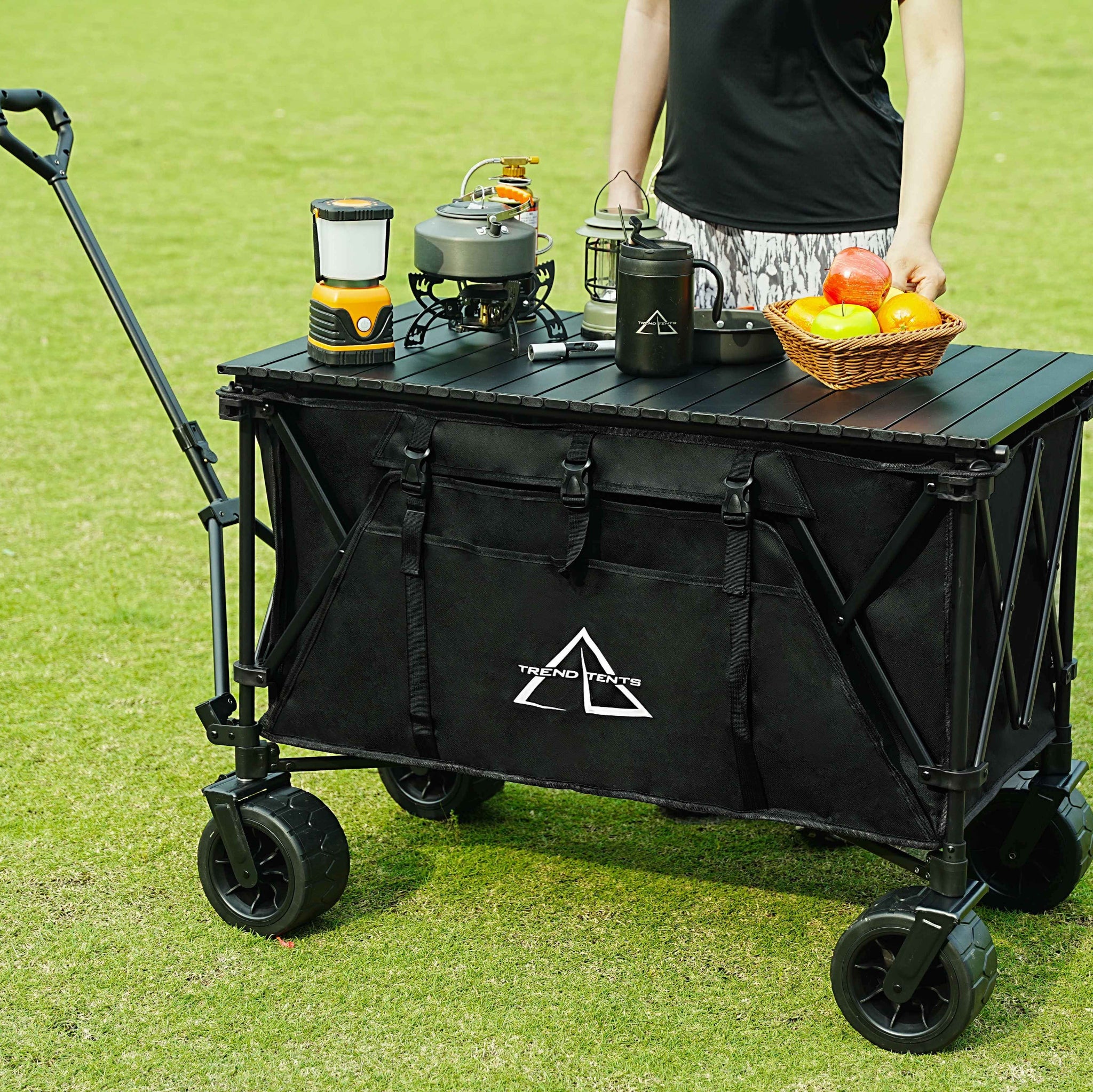 Black folding cart with camping gear on a grassy field
