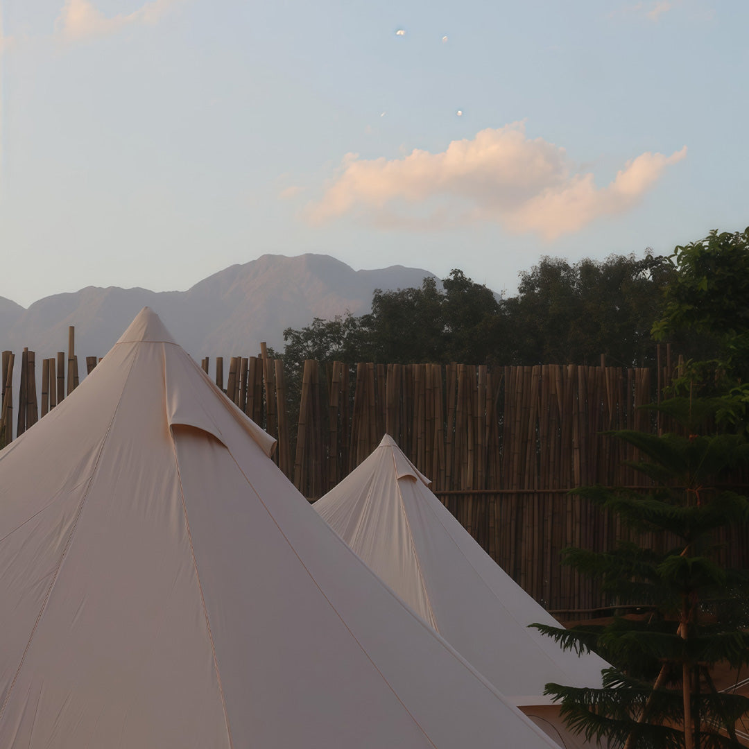 Two white tents with a mountainous landscape in the background
