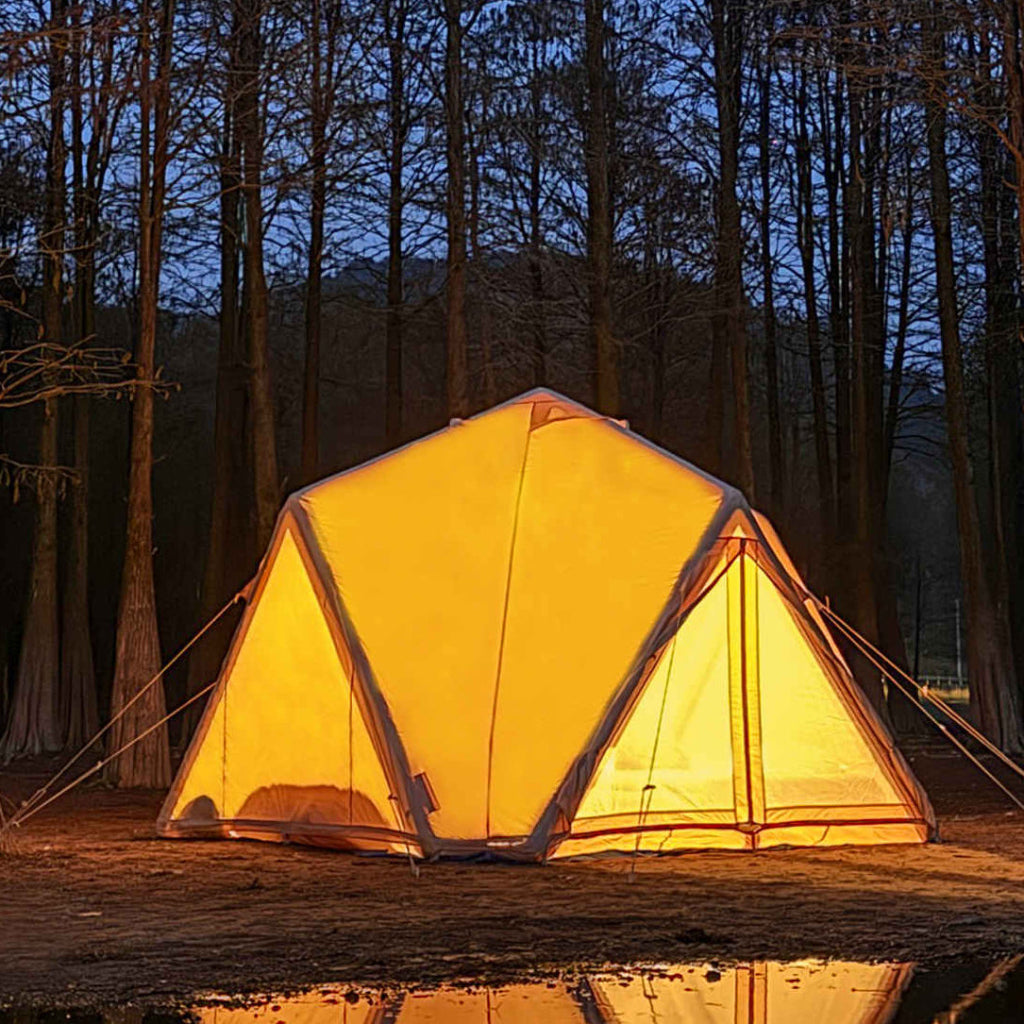 Lit tent reflected in water at night with trees in the background