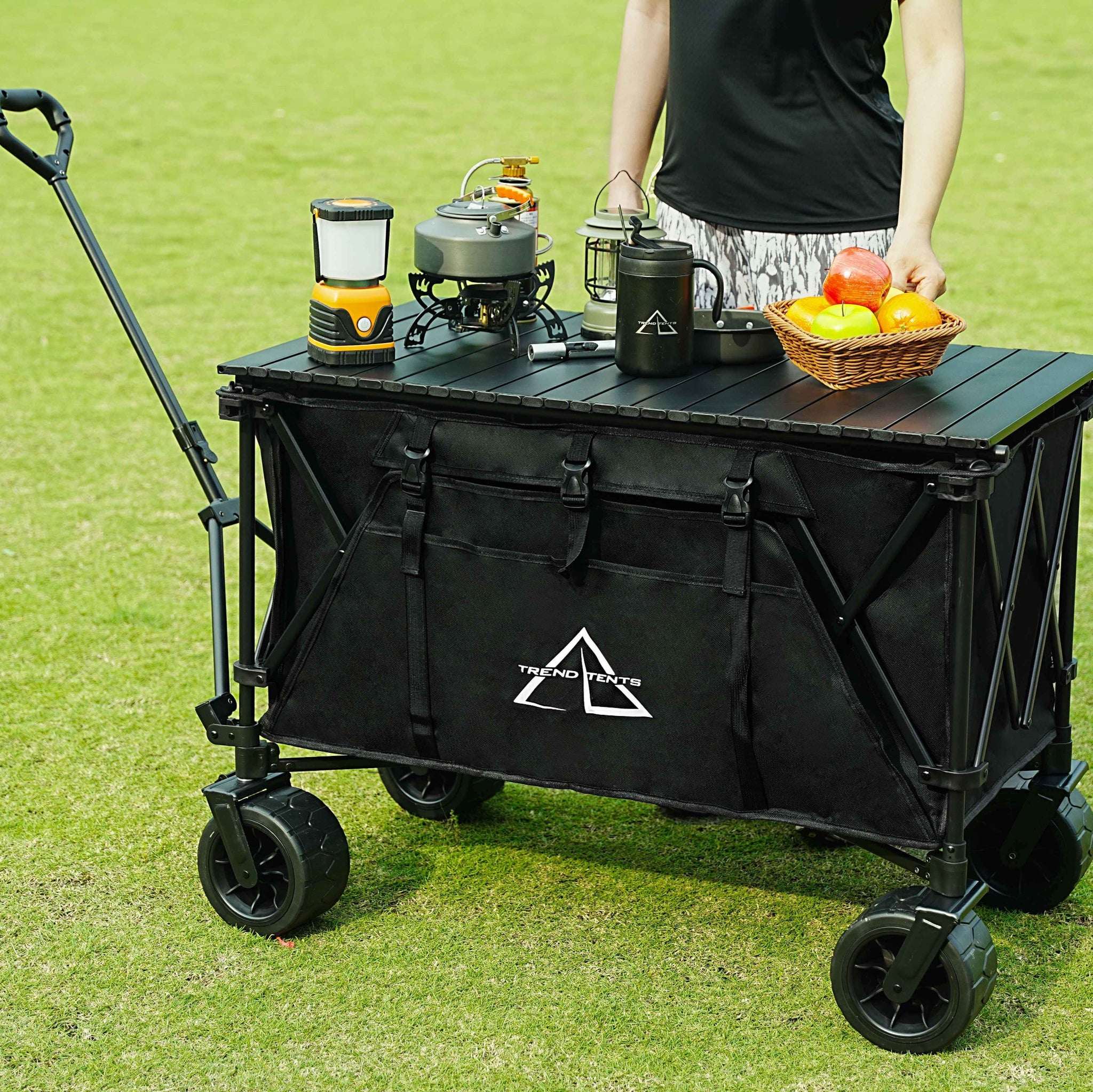 Black folding cart with camping gear on a grassy field