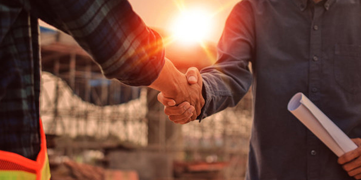 Trend Tents | Partners 
Two individuals shaking hands with a construction site in the background