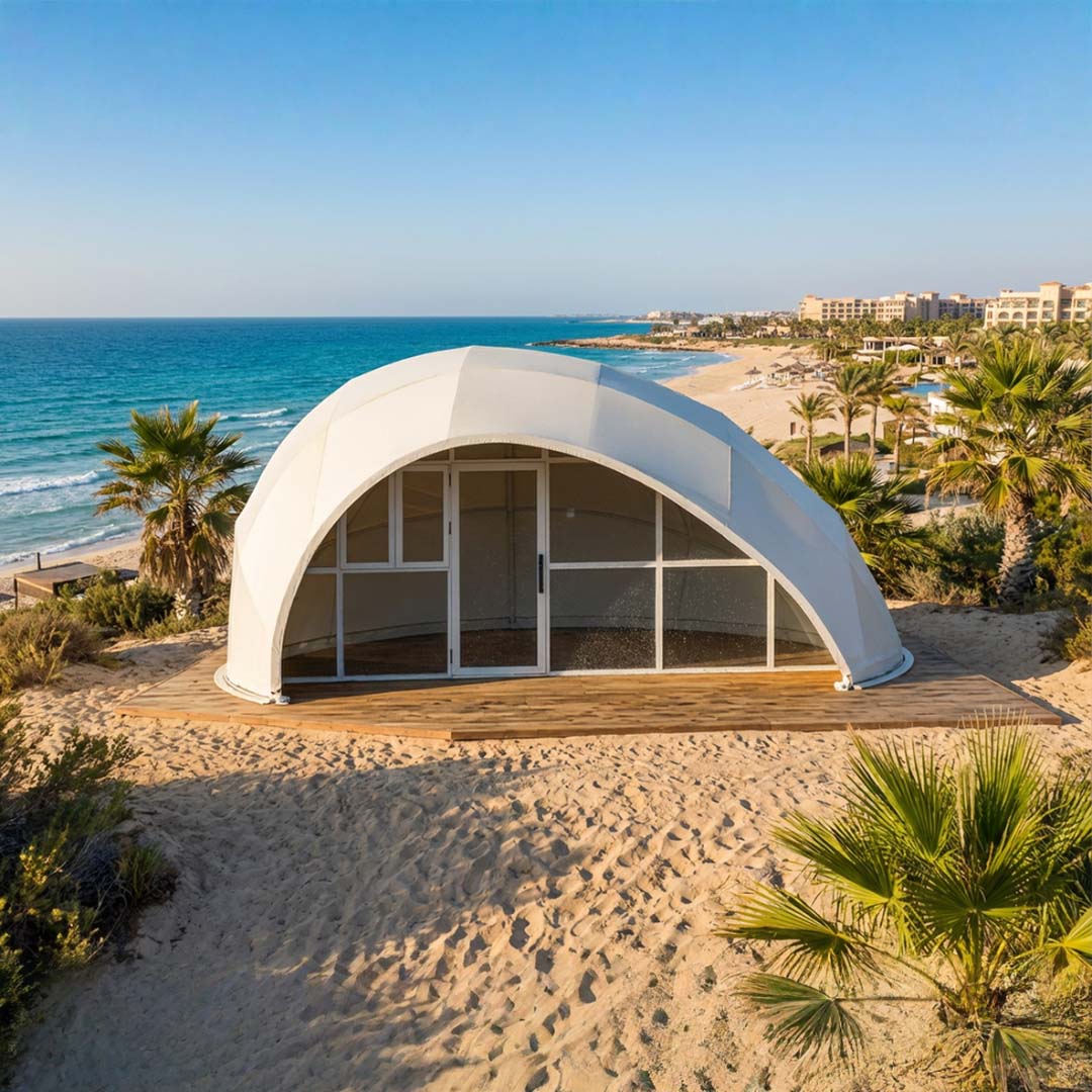 Trend Tents | Modern white dome-shaped building on a sandy beach with ocean and palm trees in the background.